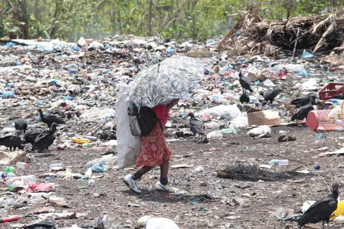 Una persona recoge desechos en un vertedero para luego venderlos y adquirir un poco de dinero.