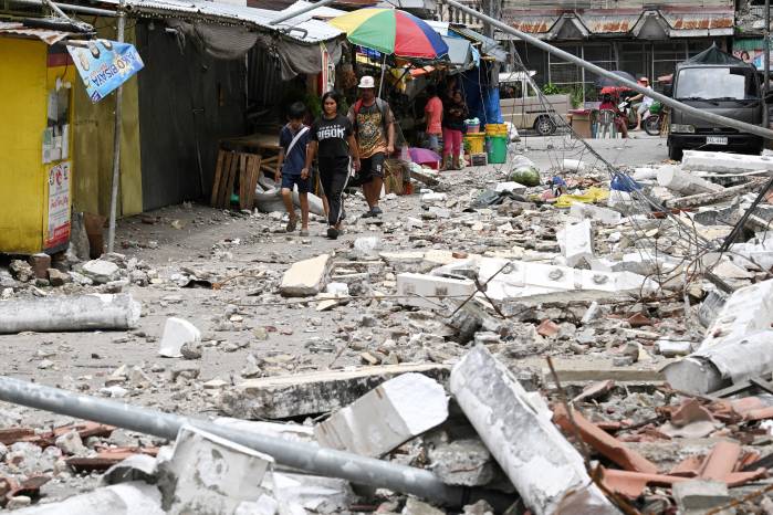 Los residentes caminan entre los escombros en la ciudad de Bogo este 1 de octubre de 2025, después de que un terremoto de magnitud 6.9 sacudiera la costa central de Filipinas la noche del 30 de septiembre.