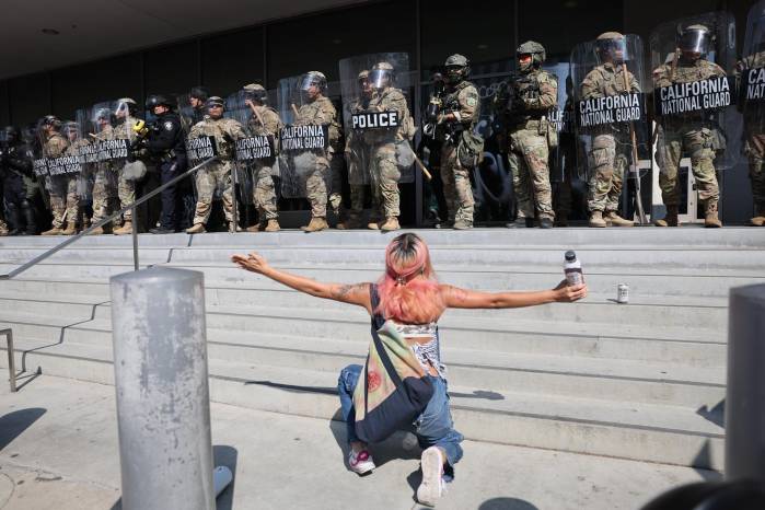 Una manifestante se arrodilla frente a miembros de la Guardia Nacional de California este lunes, frente al edificio federal Edward R. Roybal en Los Ángeles, California (Estados Unidos).