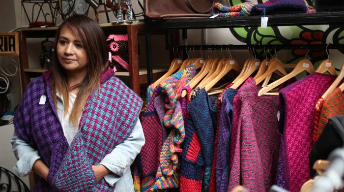 Una mujer mostrando prendas es vista al interior de una tienda que ofrece ropa confeccionada por internas de centros penitenciarios, el 6 de febrero de 2024, en La Paz (Bolivia).