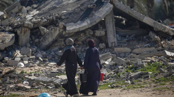Mujeres palestinas desplazadas caminan frente a las ruinas de un edificio en Deir Al Blah, al sur de la franja de Gaza.