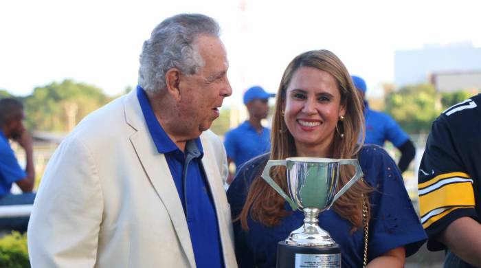 Alberto Paz Rodríguez entrega la copa del triunfo clásico a Carmen Cristina, en representación de la cuadra ganadora.