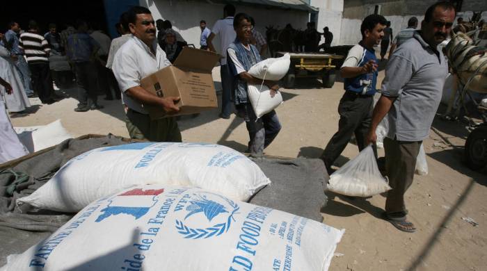 Palestinos cargan sacos de alimentos que recibieron de la Agencia de Obras Públicas y Socorro de las Naciones Unidas (UNRWA) en el campo de refugiados de al-Shati en la ciudad de Gaza el 17 de septiembre de 2008