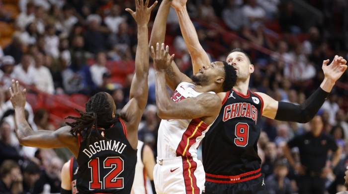 Ayo Dosunmu (i) y Nikola Vucevic, de los Chicago Bulls, en acción ante Haywood Highsmith de los Miami Heat en el partido de este viernes de la NBA en Miami, Florida. EFE/ Rhona Wise