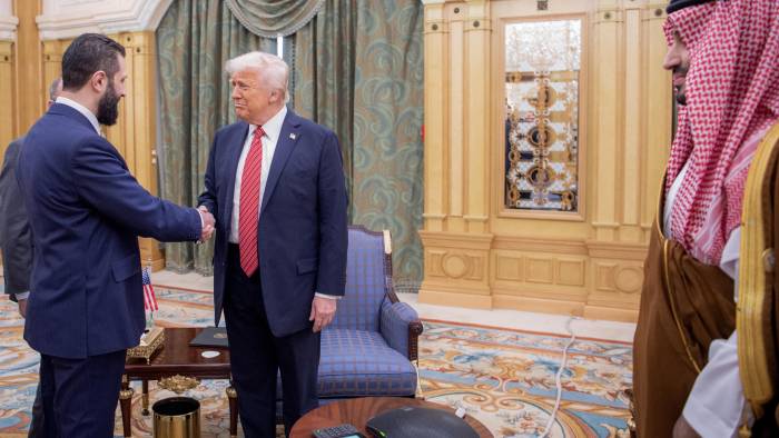 Una imagen proporcionada por el Palacio Real Saudí muestra al príncipe heredero saudí Mohammed bin Salman (der.) observando cómo el presidente estadounidense Donald Trump (centro) estrecha la mano del presidente interino sirio Ahmed al-Sharaa en Riad el 14 de mayo de 2025.