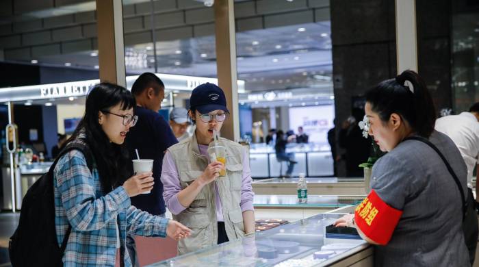 Una comerciante china atiende a jóvenes en su local comecial.