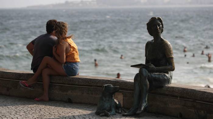 Una pareja observa el mar junto a una estatua de la escritora ucraniana-brasileña Clarice Lispector.