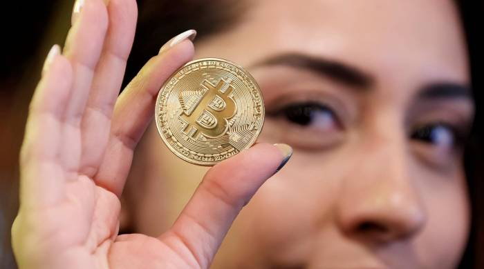 Una mujer sostiene una moneda de bitcoin en una imagen de archivo.
