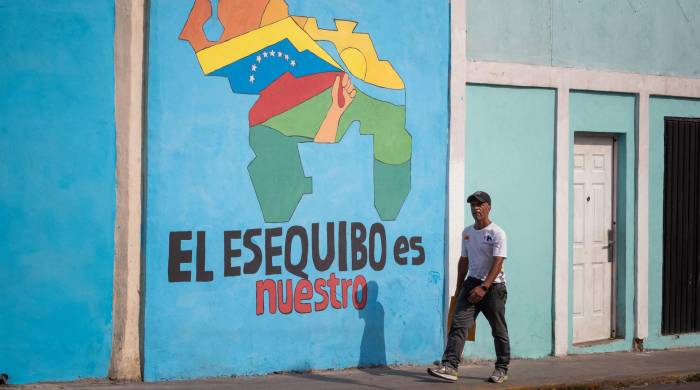Transeúntes caminan frente a un mural con el mapa de Venezuela que dice El Esequibo es nuestro, en Caracas (Venezuela), en una fotografía de archivo.