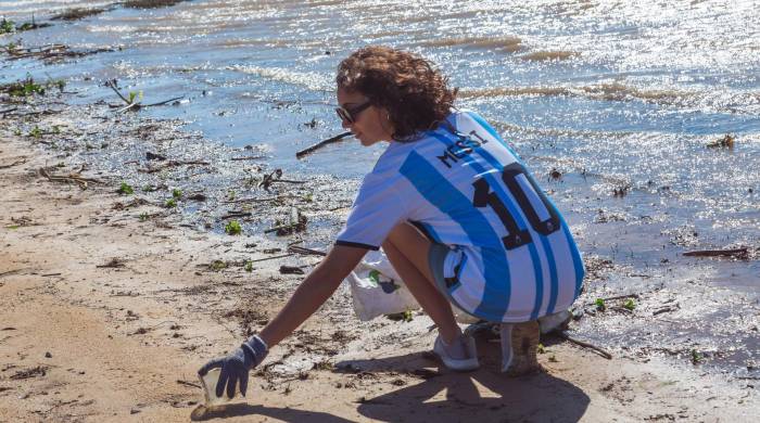 Una mujer vistiendo la camiseta del astro argentino del fútbol Lionel Messi, mientras recoge botellas de plástico del río Paraná en Rosario , Argentina.