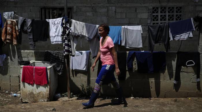 Una migrante camina frente a ropa colgada en una estación migratoria, luego de cruzar la selva del Darién con rumbo a Estados Unidos.