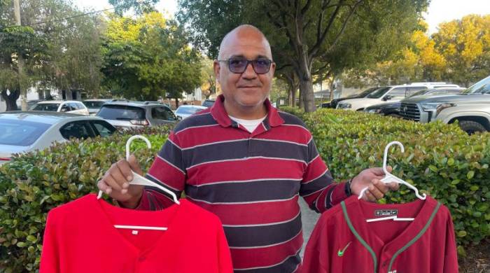 El vendedor José Godoy muestra unas camisetas de béisbol de Puerto Rico y México.
