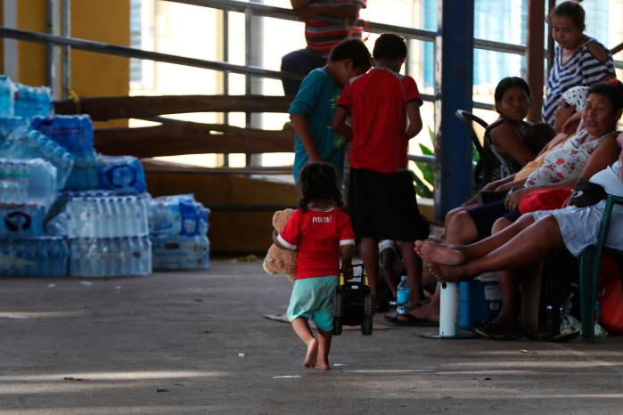 Niños juegan en una cancha junto a la Alcaldía de Mariato, Veraguas, mientras los adultos aguardan noticias sobre la evaluación de sus hogares.