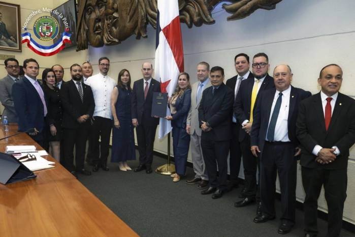 El ministro de Economía y Finanzas, Felipe Chapman (centro), recibe el documento del Presupuesto 2027 aprobado en tercer debate por la presidenta de la Asamblea Nacional, Shirley Castañedas (derecha), junto a diputados del Pleno.