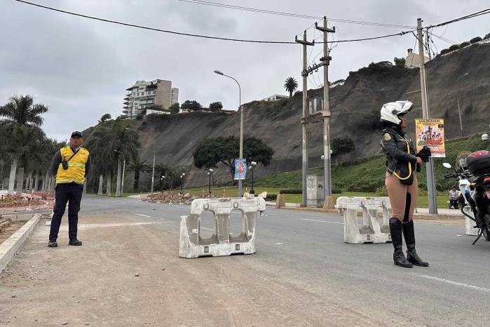 Integrantes de equipos de seguridad cierran la avenida Costa Verde por derrumbes en el acantilado, producto del sismo ocurrido este domingo, en Lima (Perú).