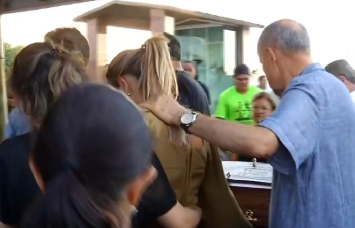 La madre de los hijos del funcionario, junto a su papá y al atáud, durante el funeral de Miguel.