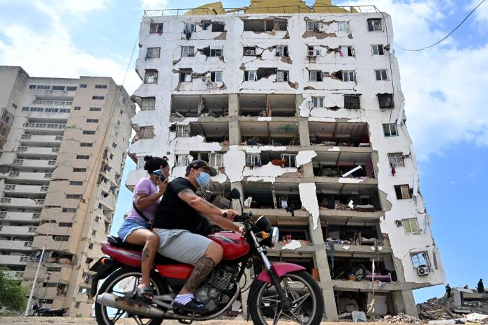 Personas circulan en motocicleta frente a un edificio de apartamentos dañado en Catia La Mar, estado La Guaira, Venezuela, el 16 de julio de 2026.