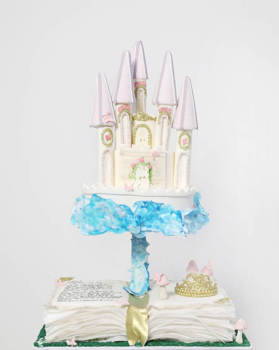 El pastel inspirado en un castillo sobre un libro abierto combina técnicas de modelado en fondant, estructuras internas reforzadas y pintura a mano.