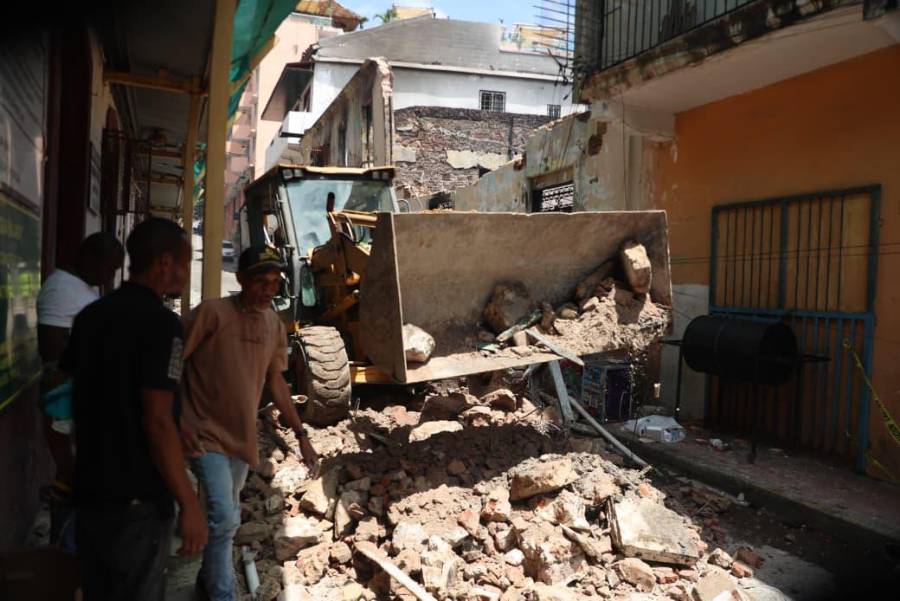 Una retroexcavadora en plena acción utiliza su pala mecánica para levantar y retirar los pesados escombros del suelo calcinado.